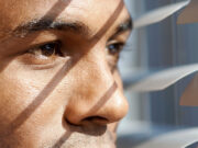 As COVID Numbers Rise, So Does ‘Psychic Numbing’ photo of man peering through blinds